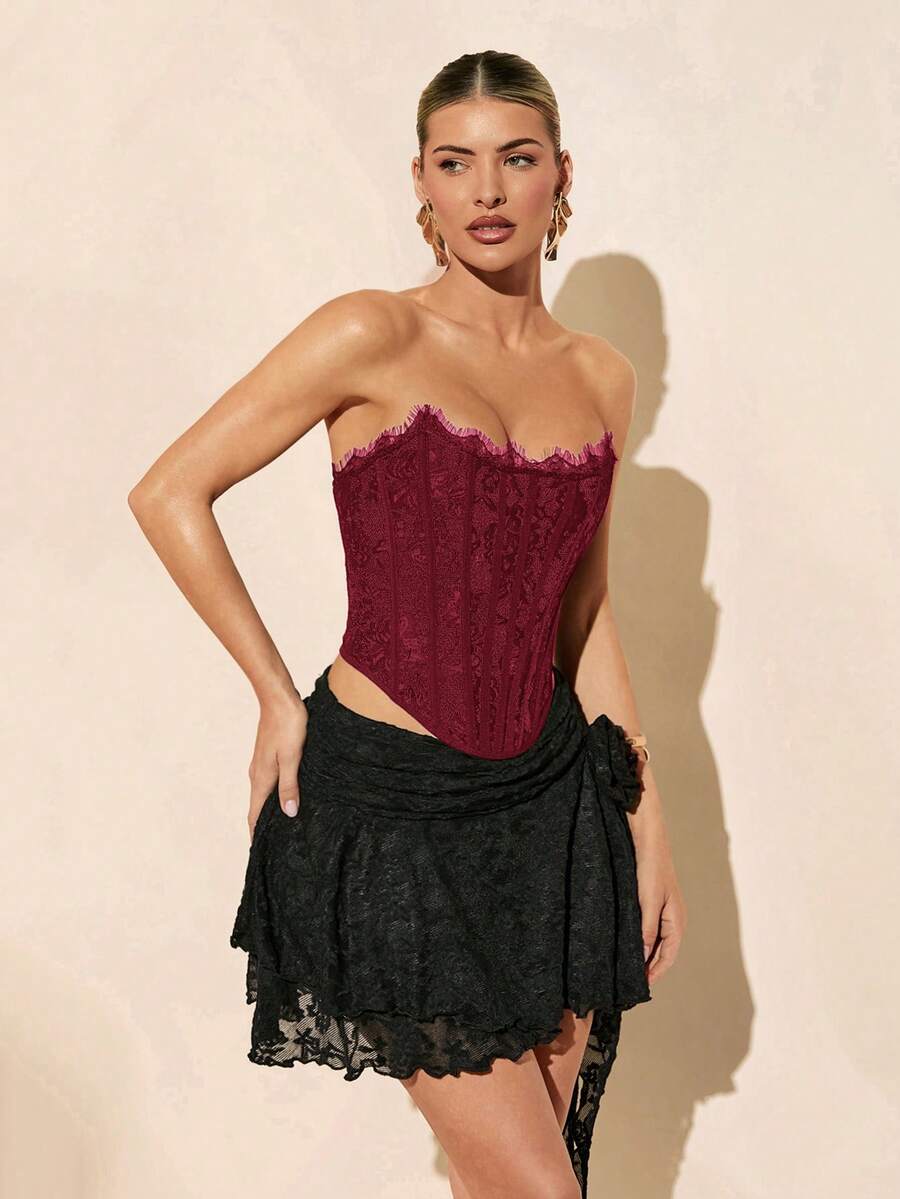 Women's strapless bustier crop top with contrast lace, lace-up detail, and an asymmetric hem in a slim-fit satin finish.