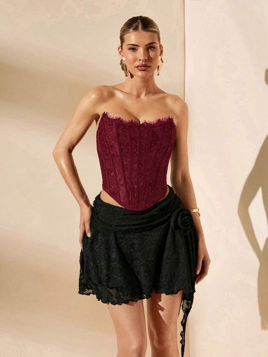 Women's strapless bustier crop top with contrast lace, lace-up detail, and an asymmetric hem in a slim-fit satin finish.