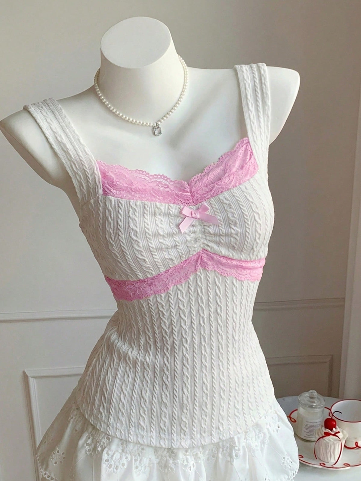 Black and white polka dot knit camisole tank top featuring delicate contrast lace trim, a cute bow accent at the sweetheart neckline, and slender shoulder straps.