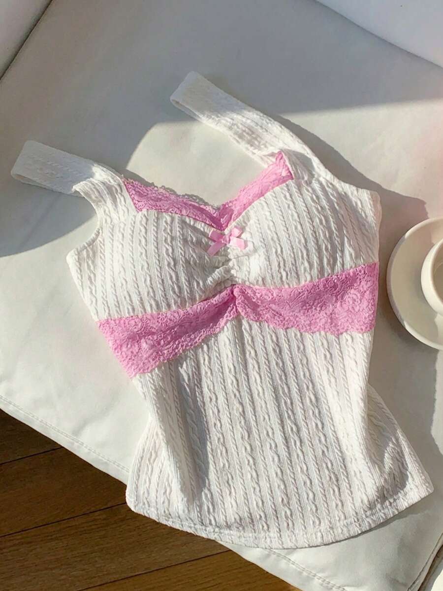 Black and white polka dot knit camisole tank top featuring delicate contrast lace trim, a cute bow accent at the sweetheart neckline, and slender shoulder straps.