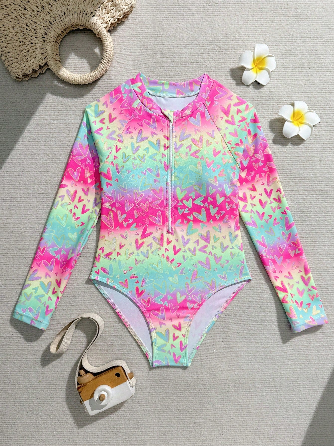 Tween girls one-piece rash guard swimsuit with long sleeves, high neck, front zipper, and ocean shell graphic print in a fitted style for beach, swimming, and vacation wear.