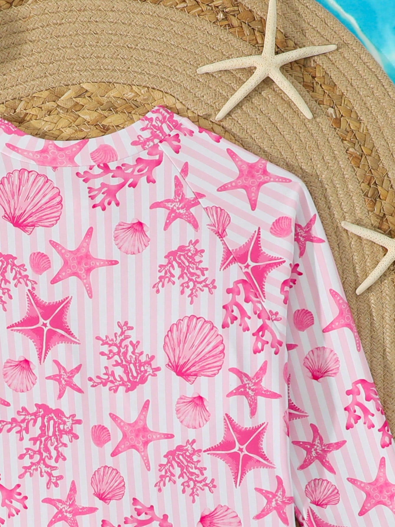 Tween girls one-piece rash guard swimsuit with long sleeves, high neck, front zipper, and ocean shell graphic print in a fitted style for beach, swimming, and vacation wear.