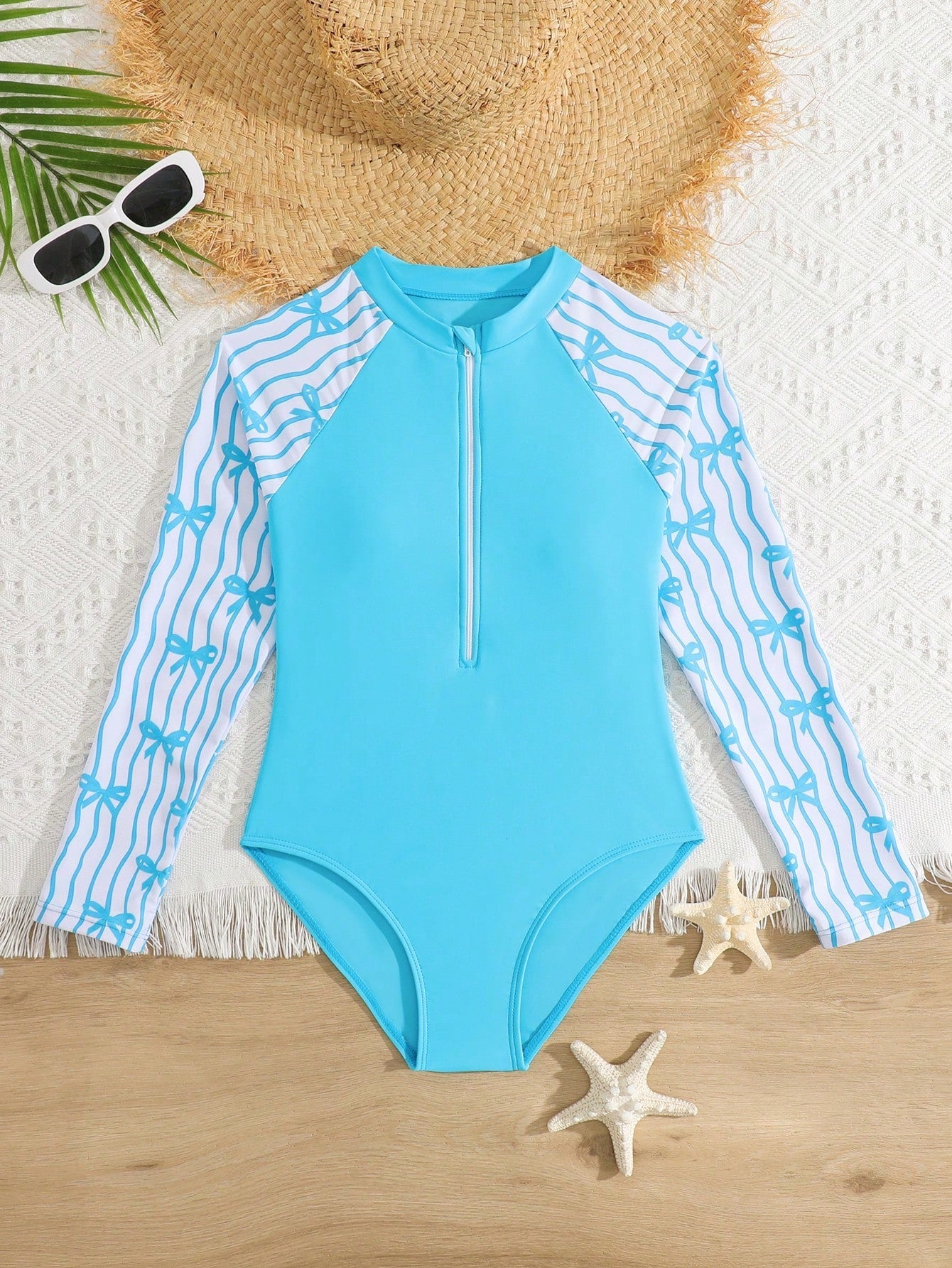Tween girls one-piece rash guard swimsuit with long sleeves, high neck, front zipper, and ocean shell graphic print in a fitted style for beach, swimming, and vacation wear.