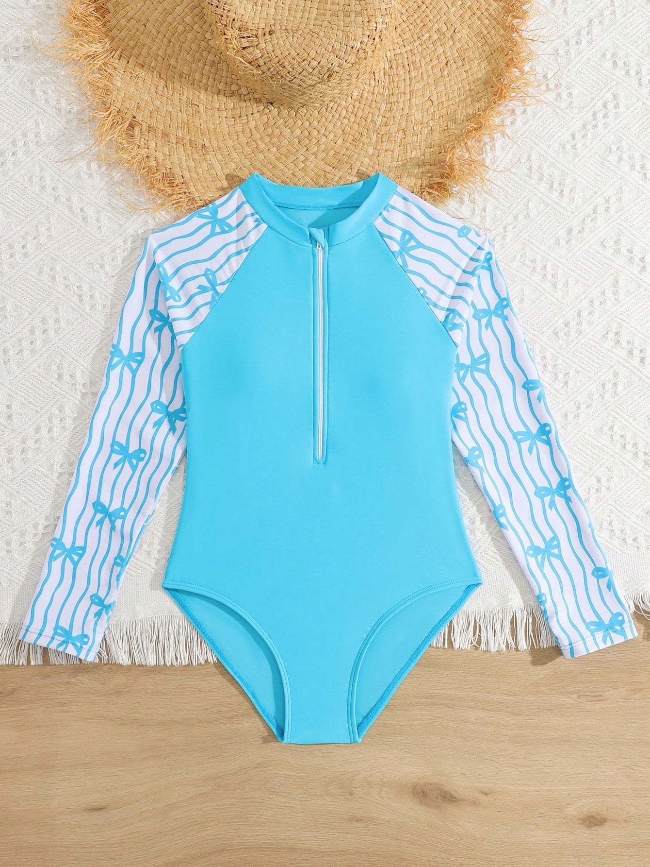Tween girls one-piece rash guard swimsuit with long sleeves, high neck, front zipper, and ocean shell graphic print in a fitted style for beach, swimming, and vacation wear.