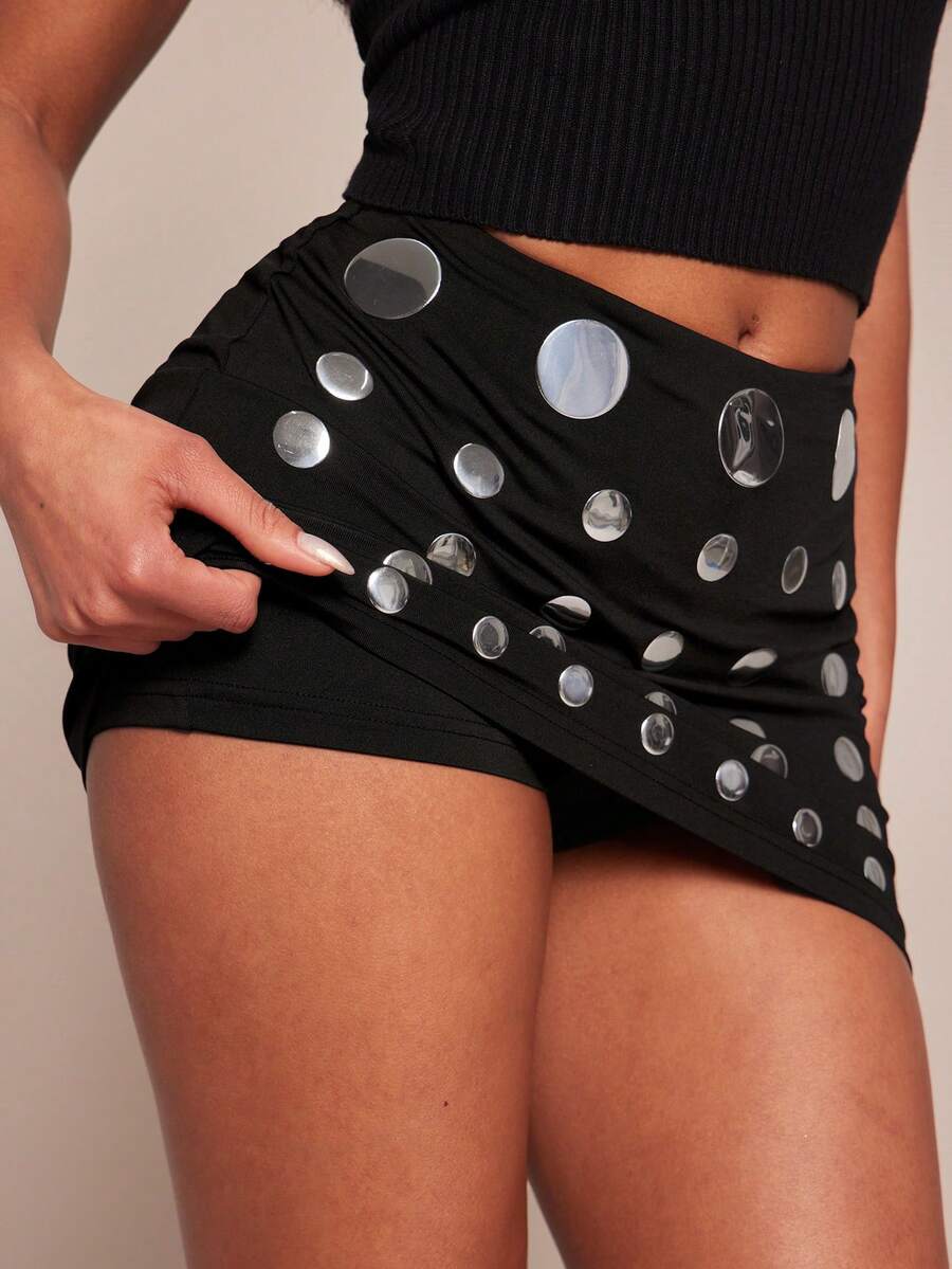 Women's black bodycon mini skort featuring a low waist, pleated side split hem, zipper closure, and built-in shorts.