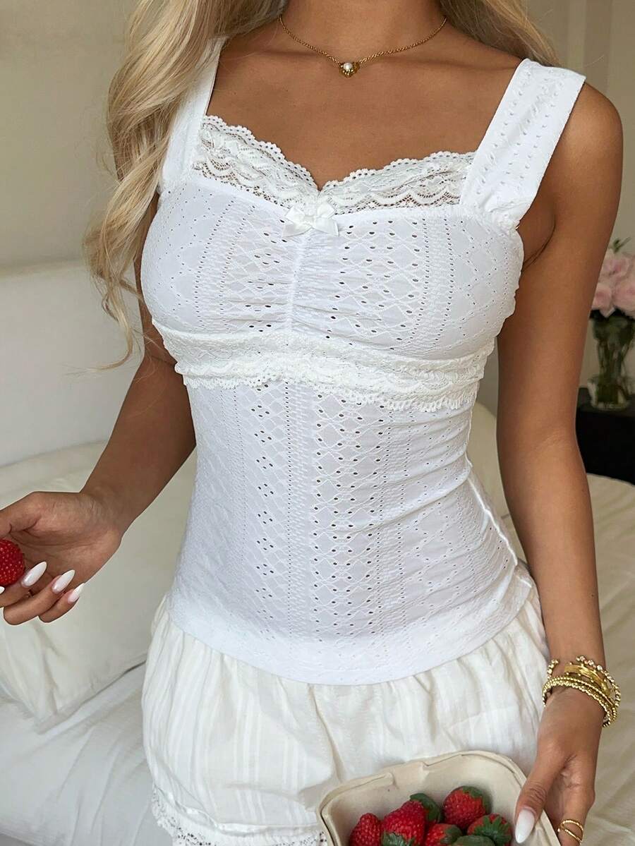 Black and white polka dot knit camisole tank top featuring delicate contrast lace trim, a cute bow accent at the sweetheart neckline, and slender shoulder straps.