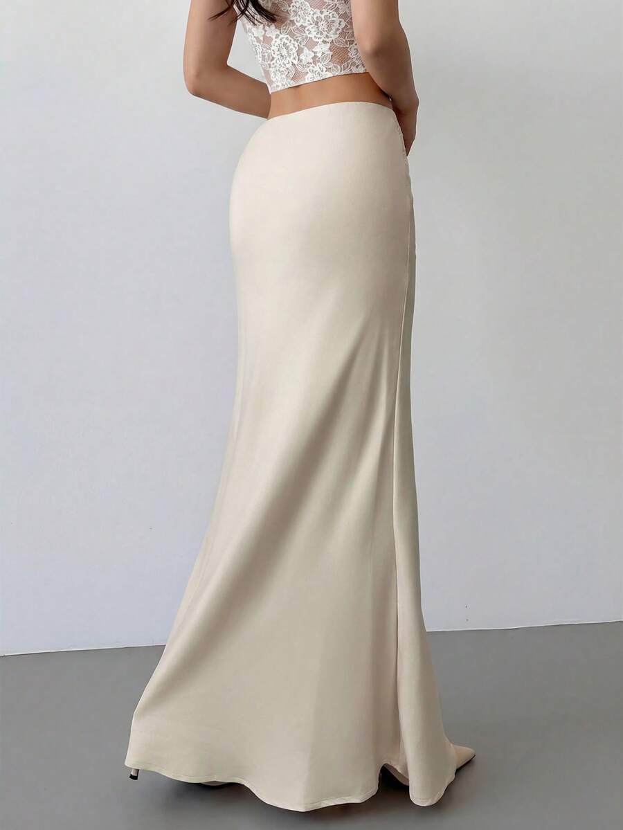 Women's apricot satin fishtail maxi skirt featuring a low waist, slit detail, lined body, and zipper closure.