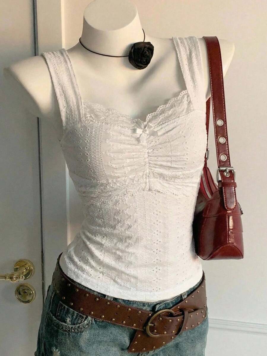 Black and white polka dot knit camisole tank top featuring delicate contrast lace trim, a cute bow accent at the sweetheart neckline, and slender shoulder straps.