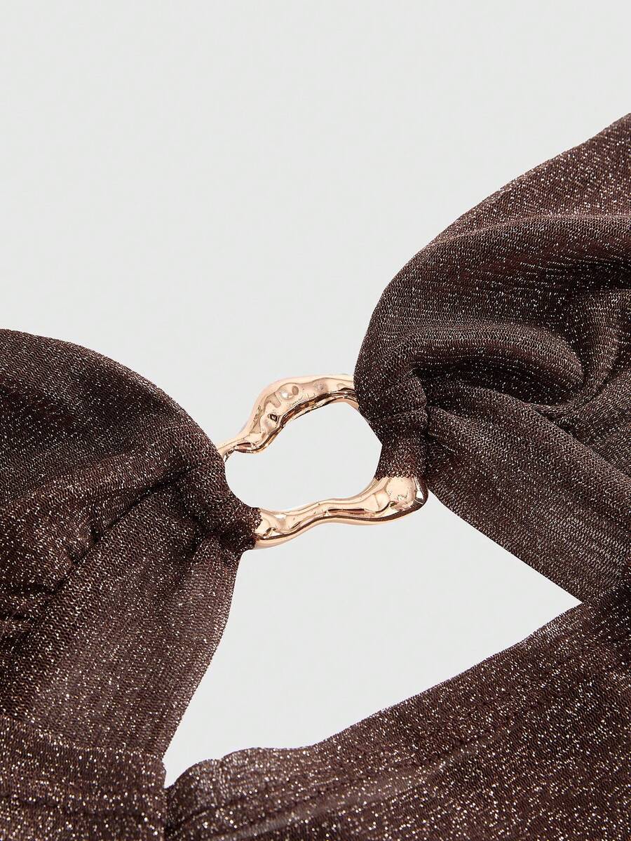 Women's glitter backless halter crop top with a draped neck and tie-up straps in metallic black knit fabric.