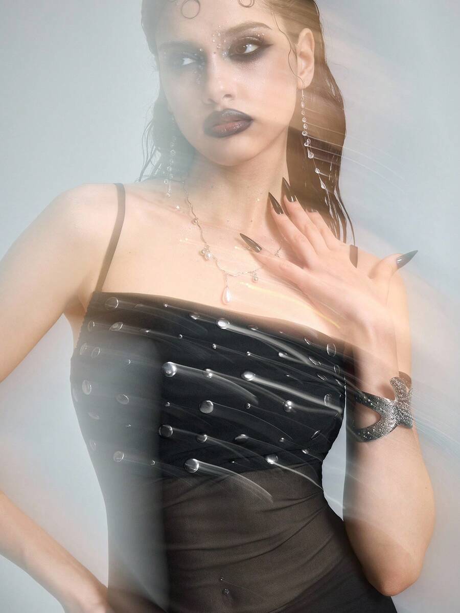 Black semi-sheer goth bodycon mini dress featuring spaghetti straps, studded details, flounce hem, and mesh fabric.