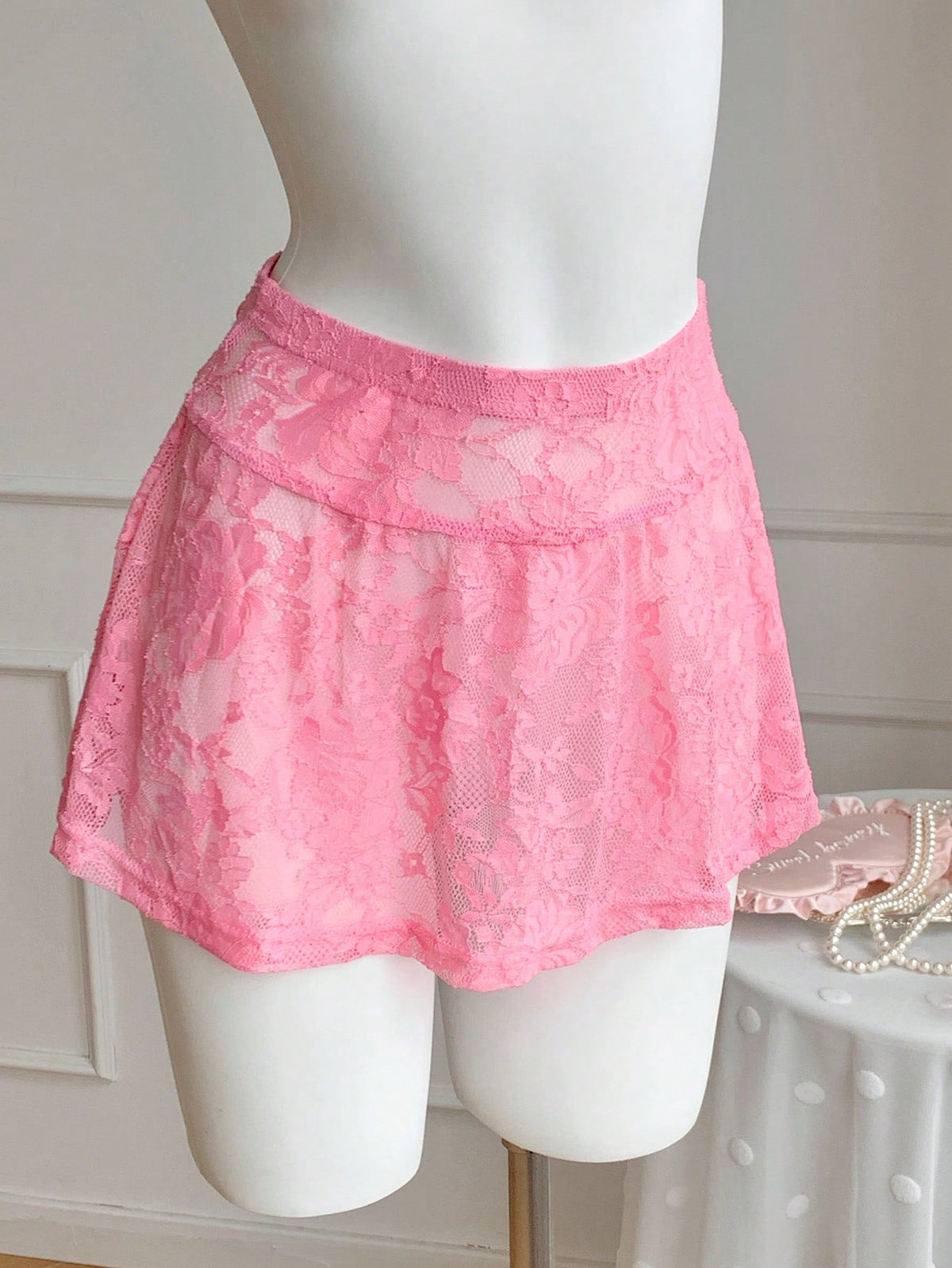 Women's black semi-sheer knitted lace mini skirt featuring a flared ruffle hem and low waist design