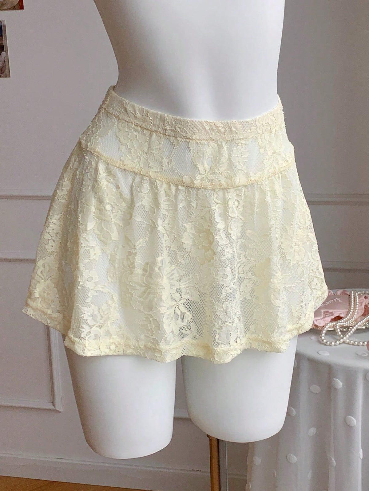 Women's black semi-sheer knitted lace mini skirt featuring a flared ruffle hem and low waist design