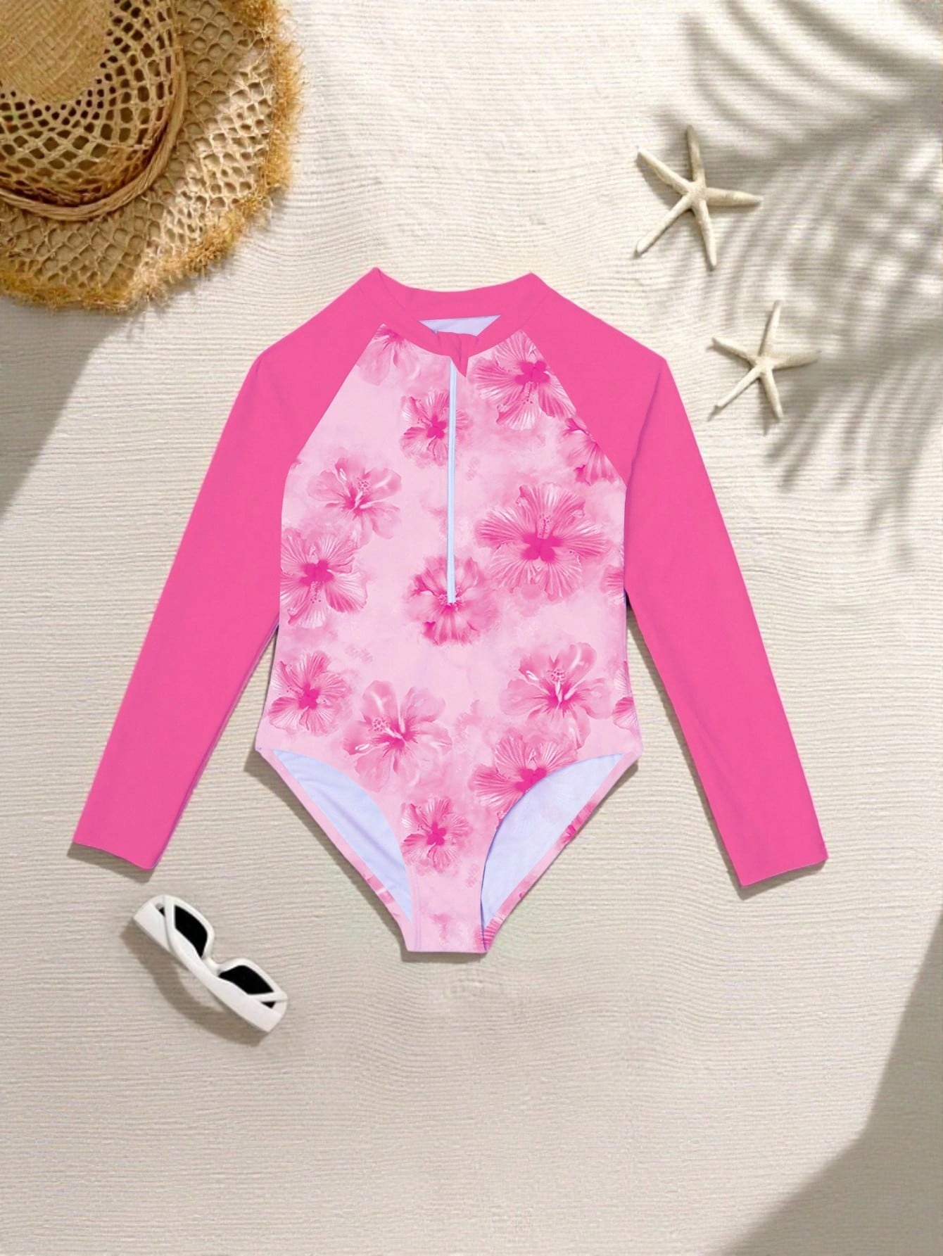 Tween girls one-piece rash guard swimsuit with long sleeves, high neck, front zipper, and ocean shell graphic print in a fitted style for beach, swimming, and vacation wear.