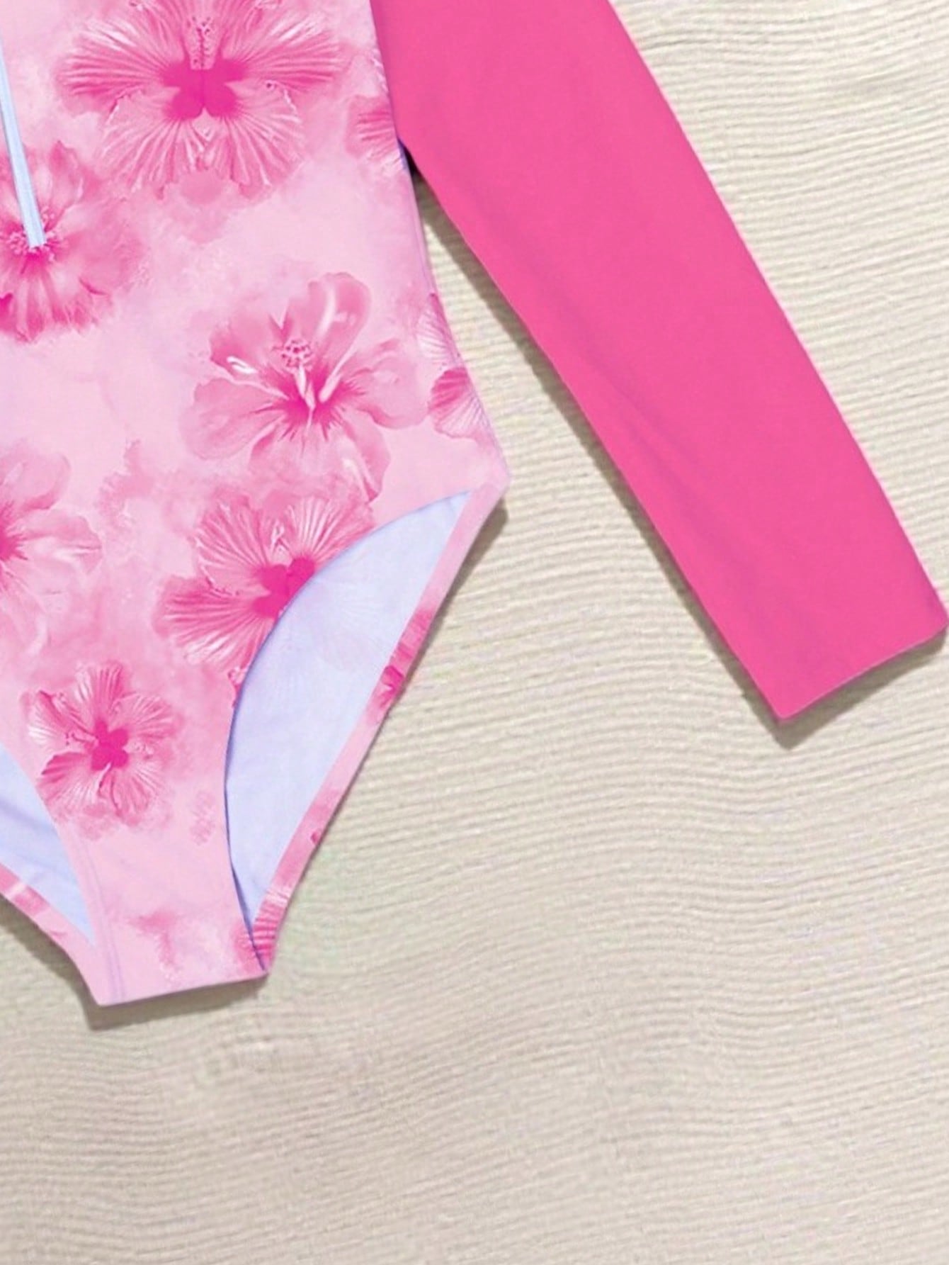 Tween girls one-piece rash guard swimsuit with long sleeves, high neck, front zipper, and ocean shell graphic print in a fitted style for beach, swimming, and vacation wear.