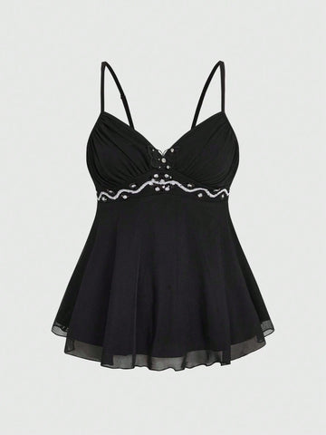 Women's black slim-fit camisole top featuring ruched body design, decorative chain accent, ruffle hem, and cold-shoulder spaghetti straps.