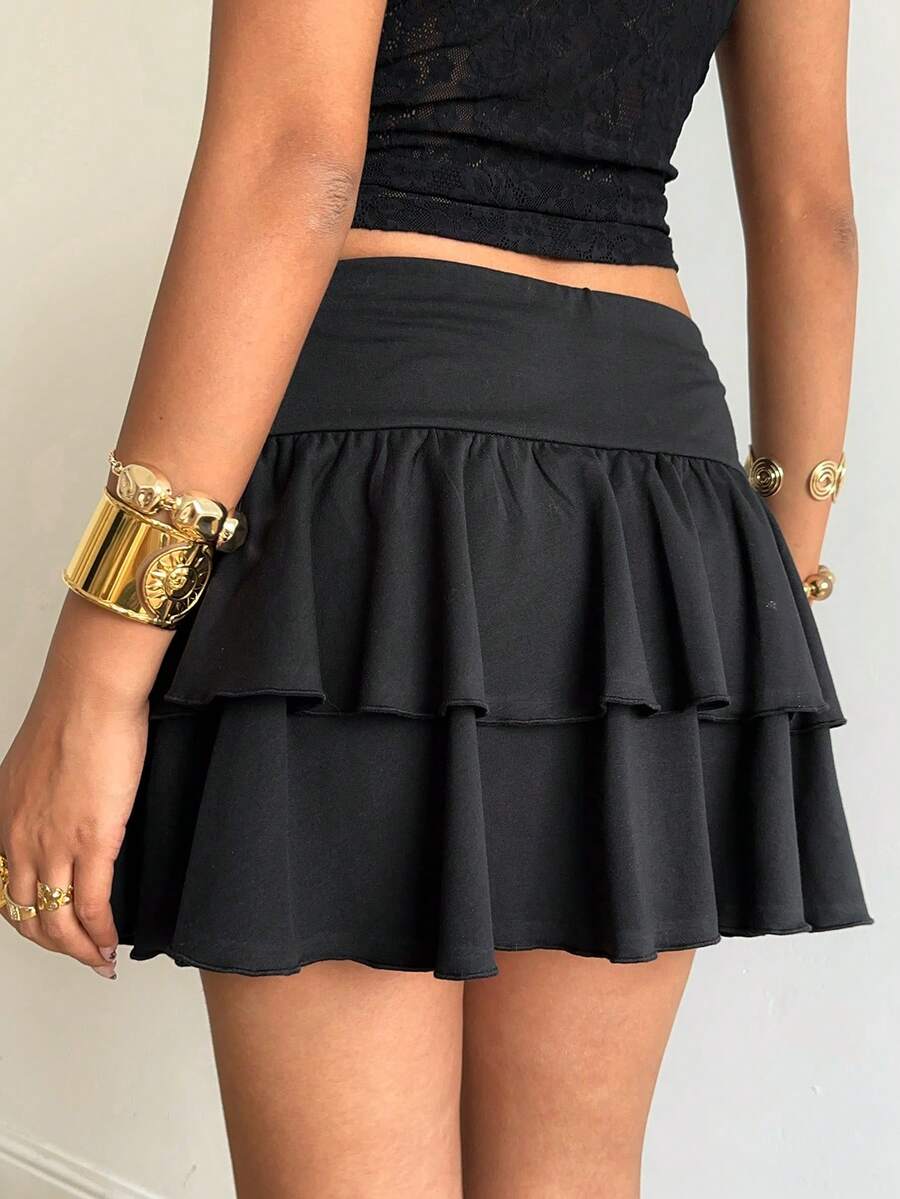 Black low waist knit mini skirt featuring a tiered ruffle hem and skinny high stretch fit.