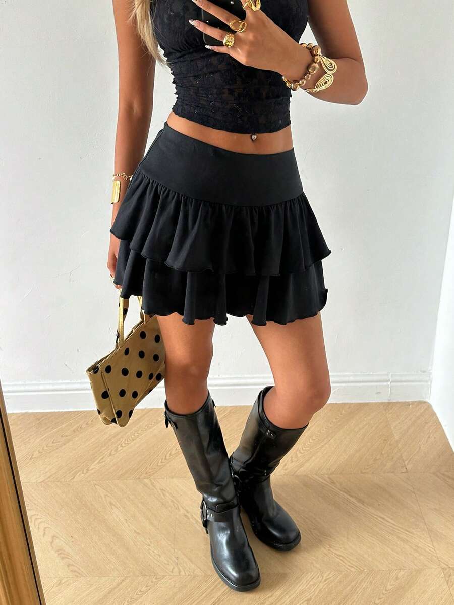 Black low waist knit mini skirt featuring a tiered ruffle hem and skinny high stretch fit.