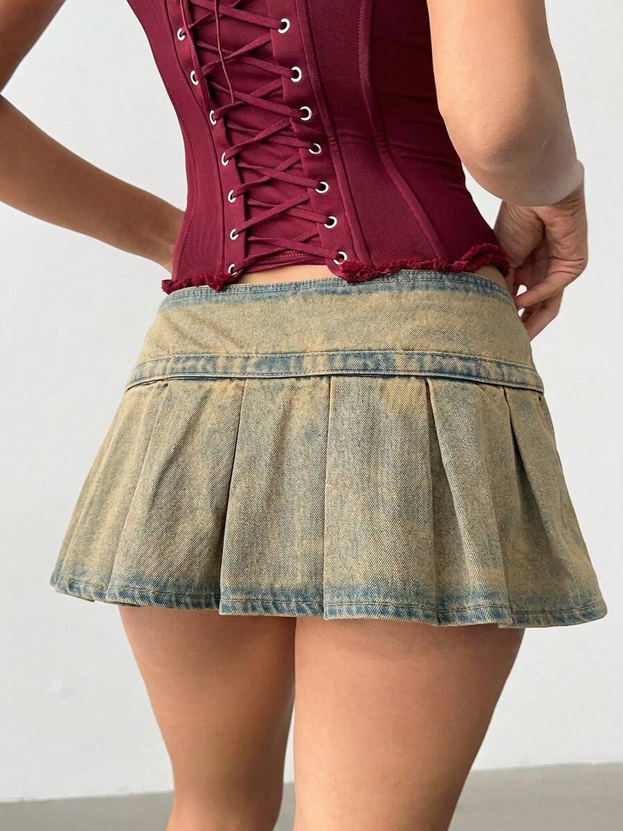Women's blue denim pleated mini skirt skort featuring a low waist fit with zipper and grommet eyelet details.