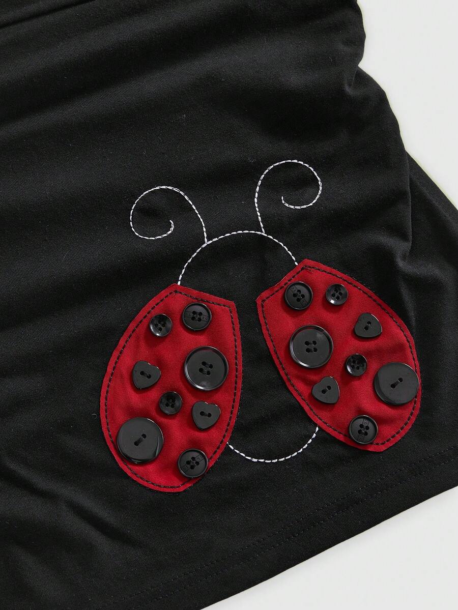 Women's black cropped strapless camisole top with ladybug embroidery and rhinestone details.