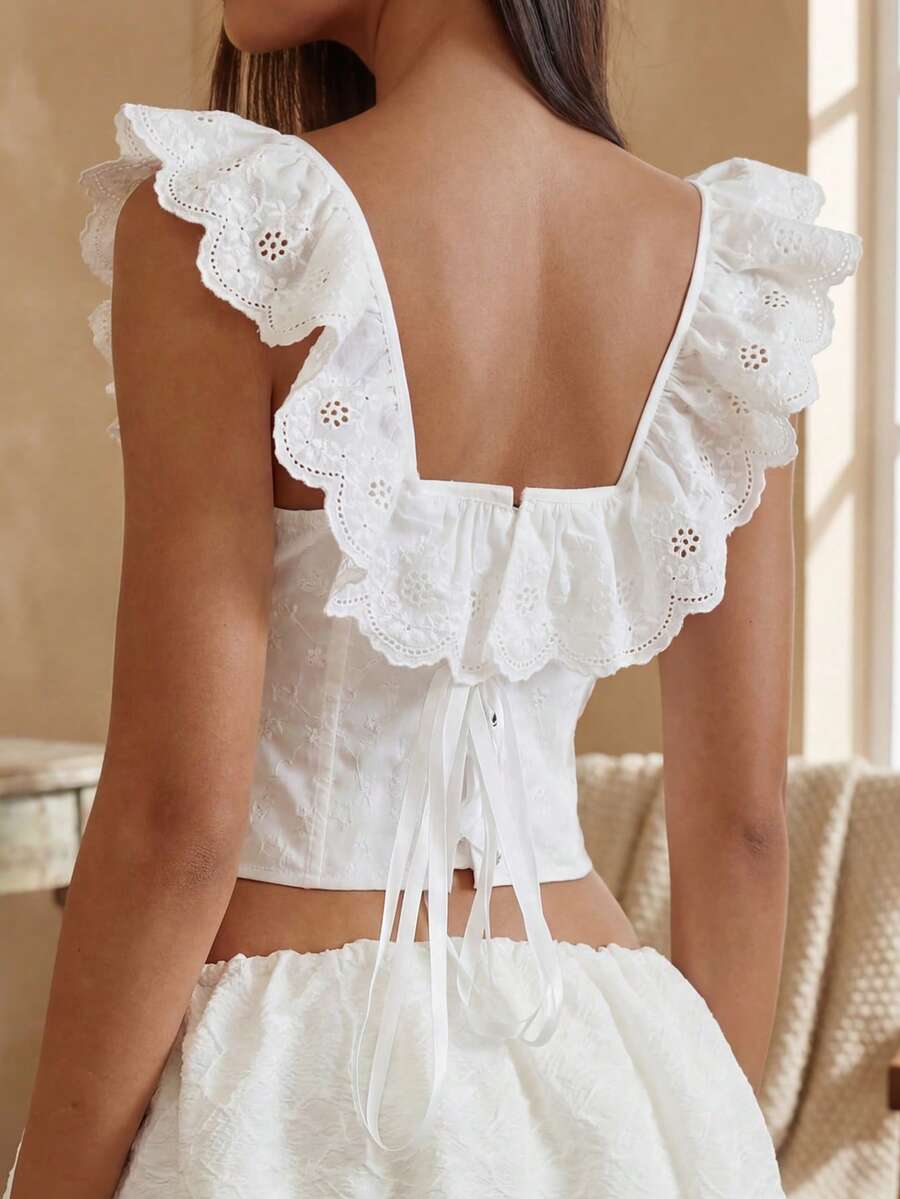 Women’s white corset top with embroidered ruffle trim, off-shoulder neckline, lace-up details, front hook closure, and sleeveless crop fit.
