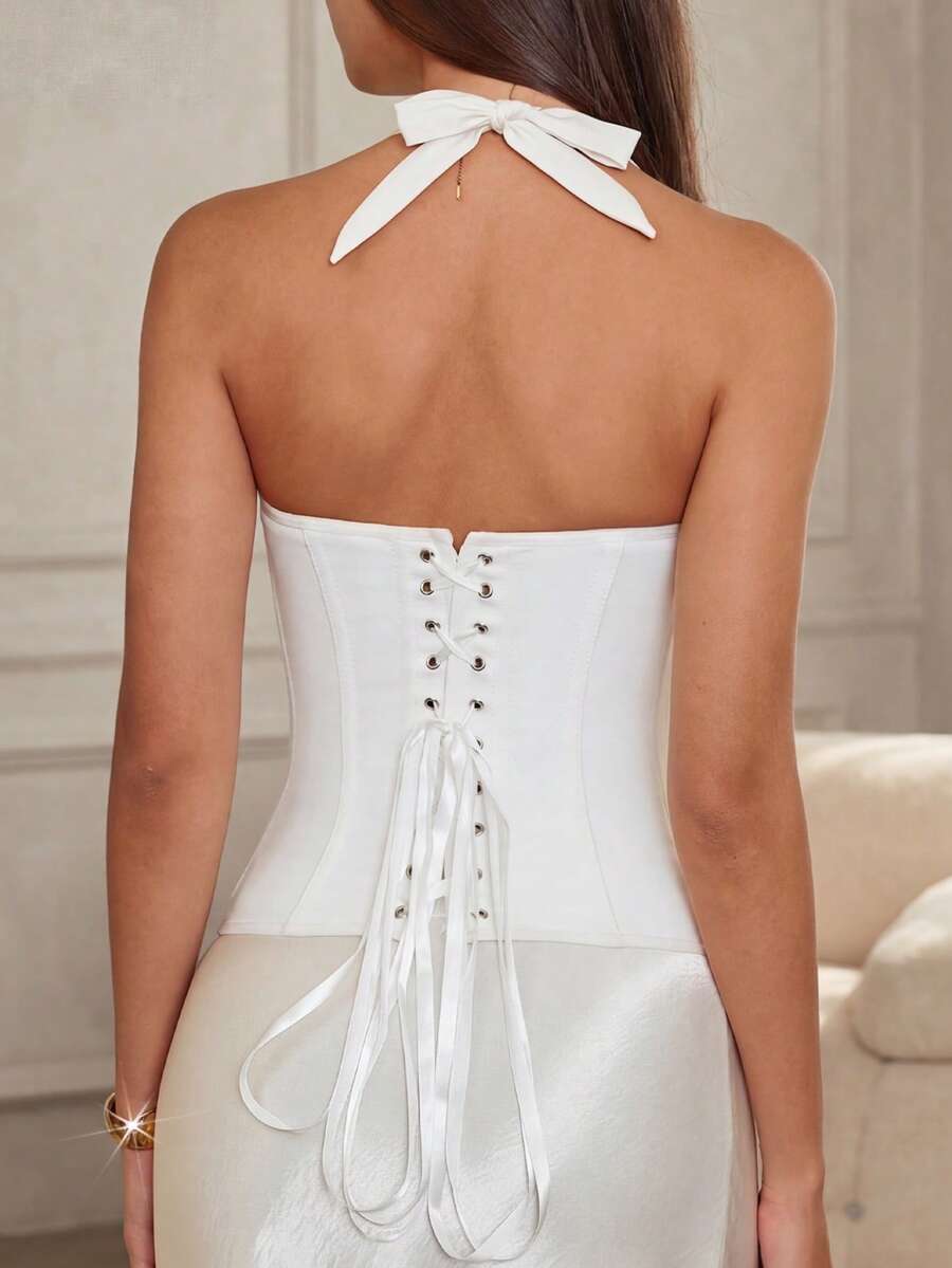 Women's white Y2K style corset cami top featuring a halter neckline, ruched detailing, asymmetrical hem, and backless lace-up design.