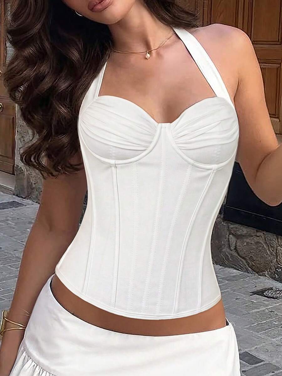Women's white Y2K style corset cami top featuring a halter neckline, ruched detailing, asymmetrical hem, and backless lace-up design.