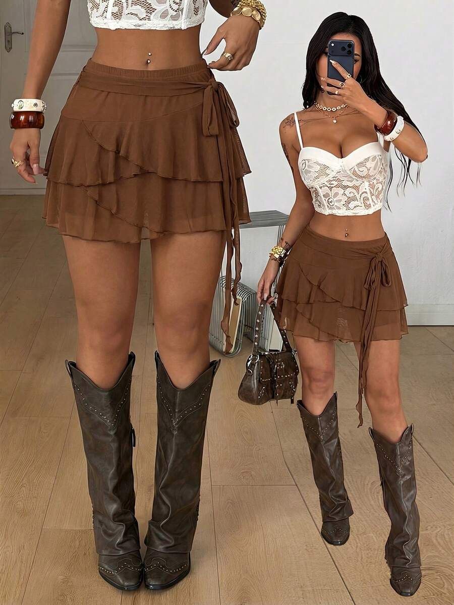 Black low waist tiered mini skirt featuring a ruffle hem and ring accent detail on knitted stretch fabric for women.