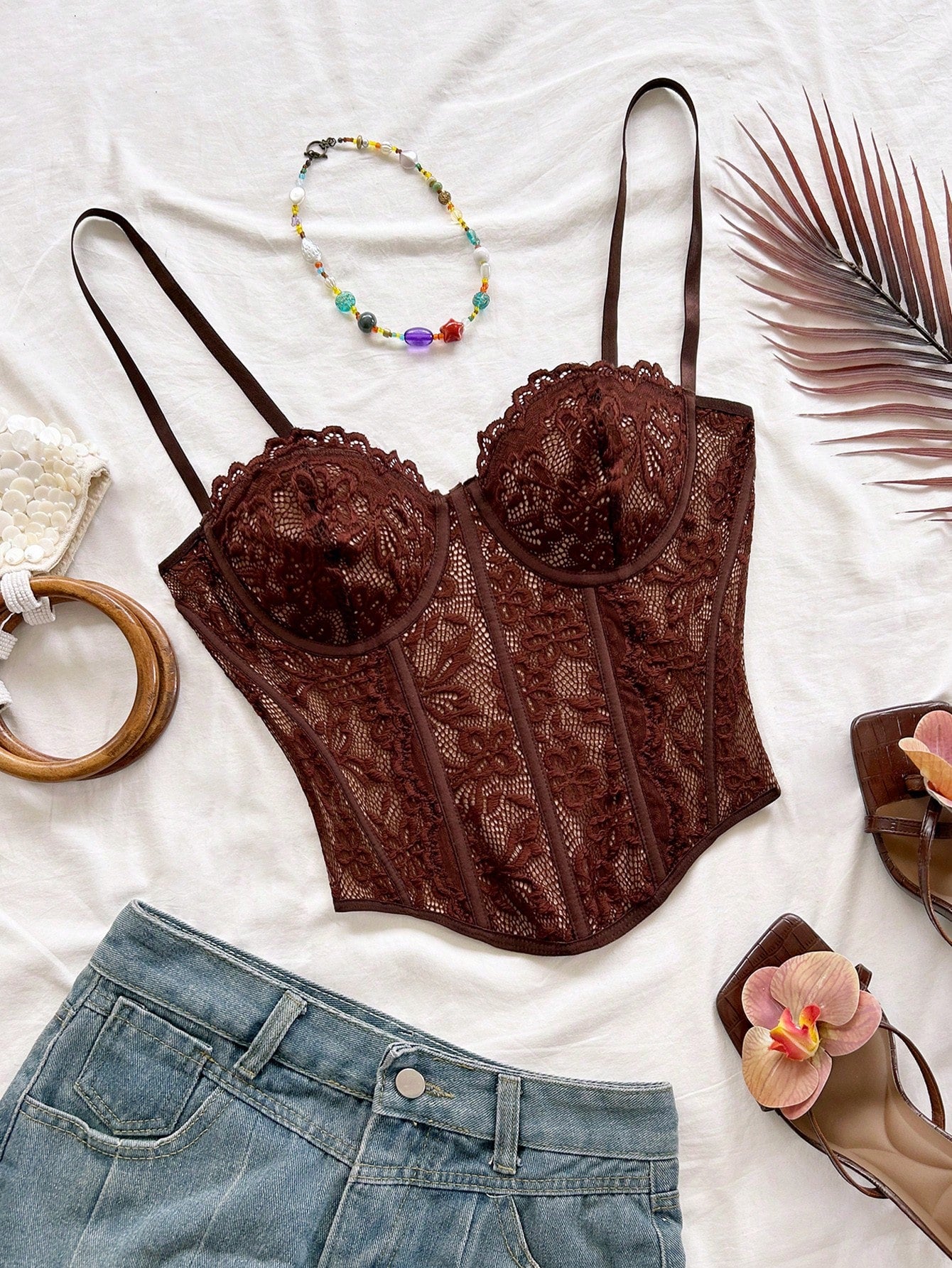 Women's lace bustier camisole top with spaghetti straps, contrast lace, lace-up detail, and an asymmetrical hem in a slim fit design.