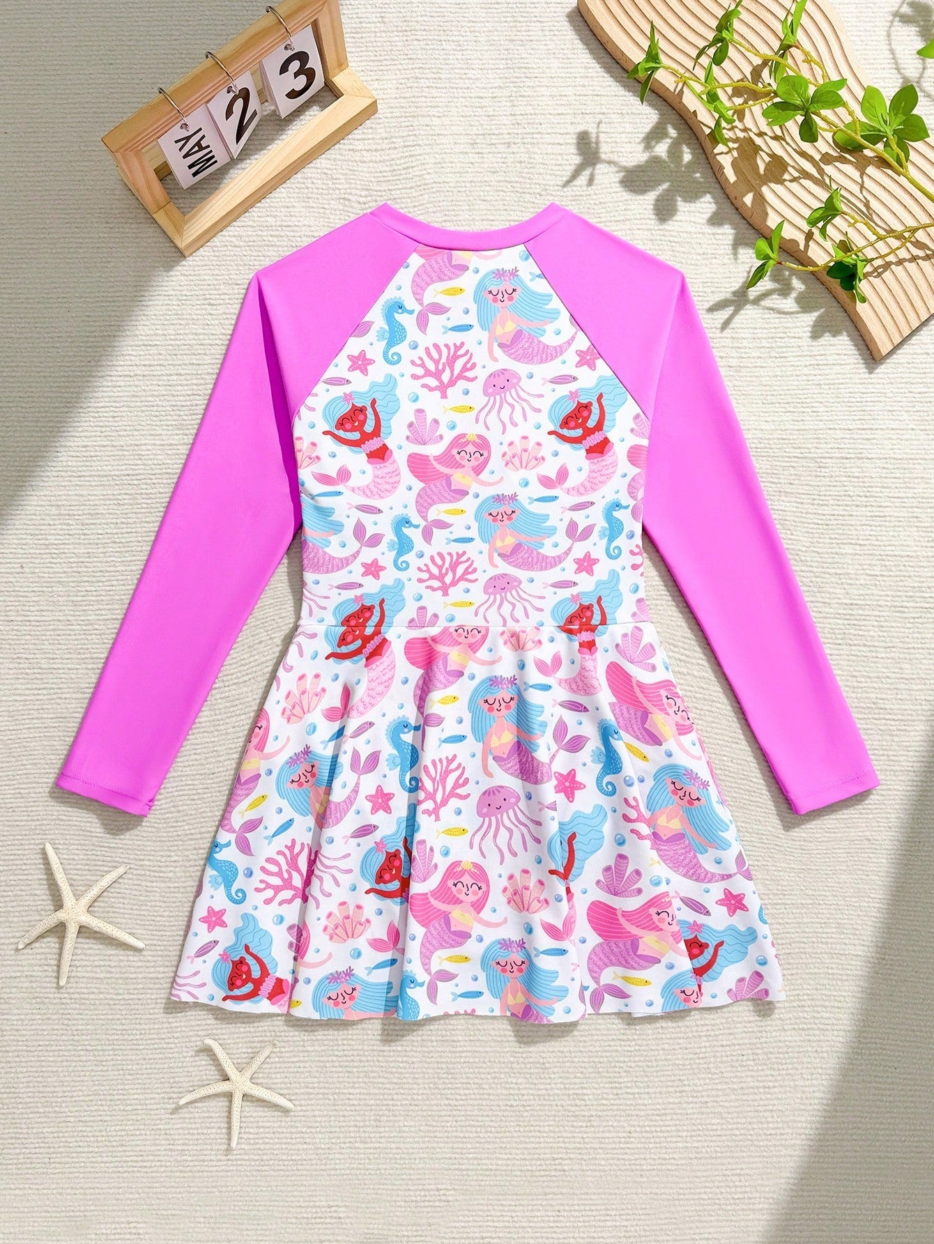Tween girls one-piece rash guard swimsuit with long sleeves, high neck, front zipper, and ocean shell graphic print in a fitted style for beach, swimming, and vacation wear.