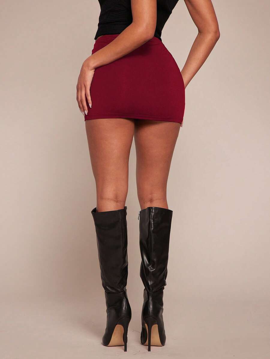 Women's black bodycon mini skort featuring a low waist, pleated side split hem, zipper closure, and built-in shorts.