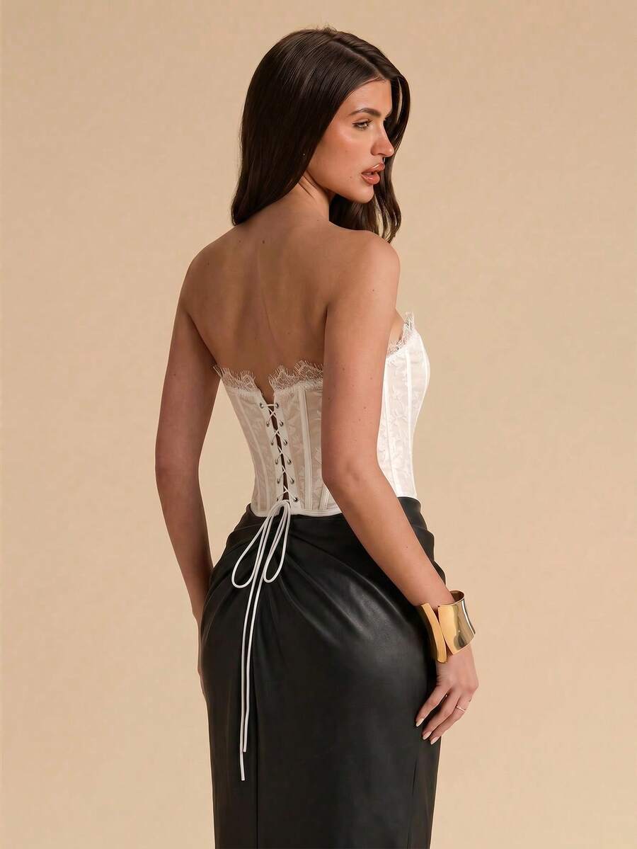 Women's strapless bustier crop top with contrast lace, lace-up detail, and an asymmetric hem in a slim-fit satin finish.