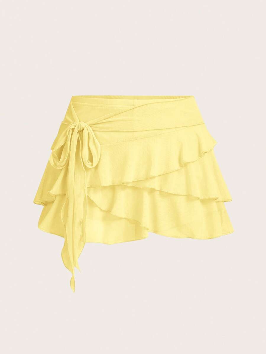 White tiered ruffle trim mini skirt for women with low waist, knot detail, mesh fabric, and casual Y2K boho design.