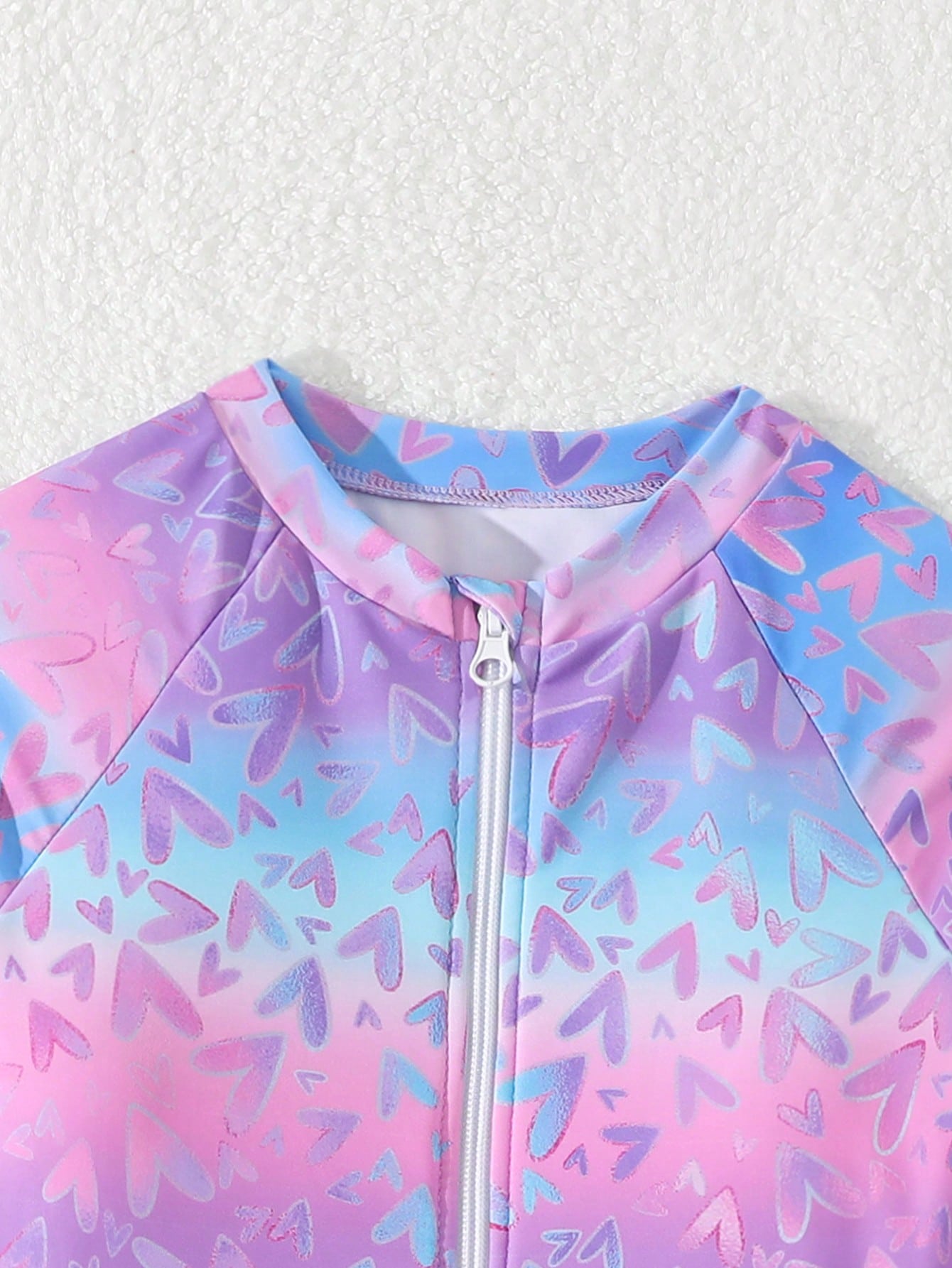 Tween girls one-piece rash guard swimsuit with long sleeves, high neck, front zipper, and ocean shell graphic print in a fitted style for beach, swimming, and vacation wear.