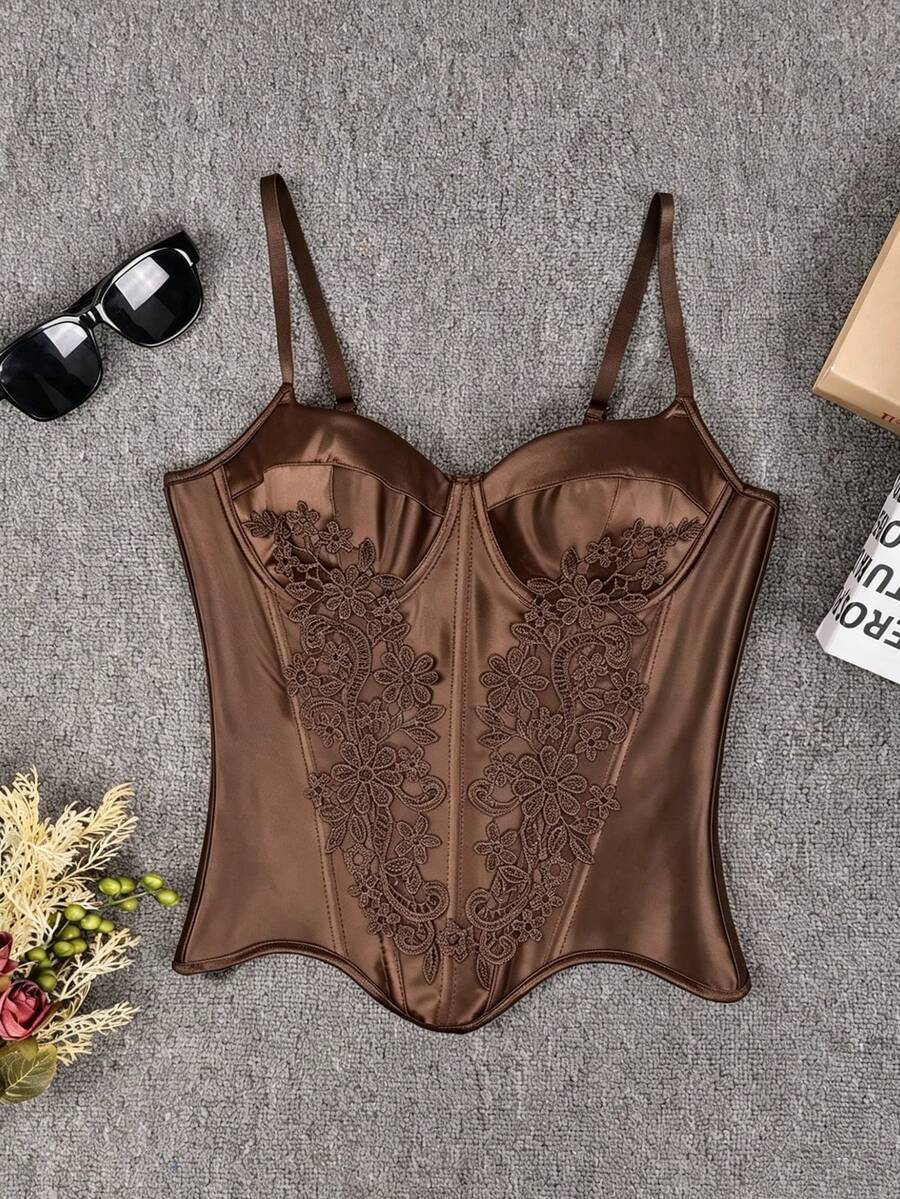 Black satin corset top for women with 3D floral rose details, boned slim-fit bodice, thin spaghetti straps, lace-up open back, and asymmetrical curved hem.