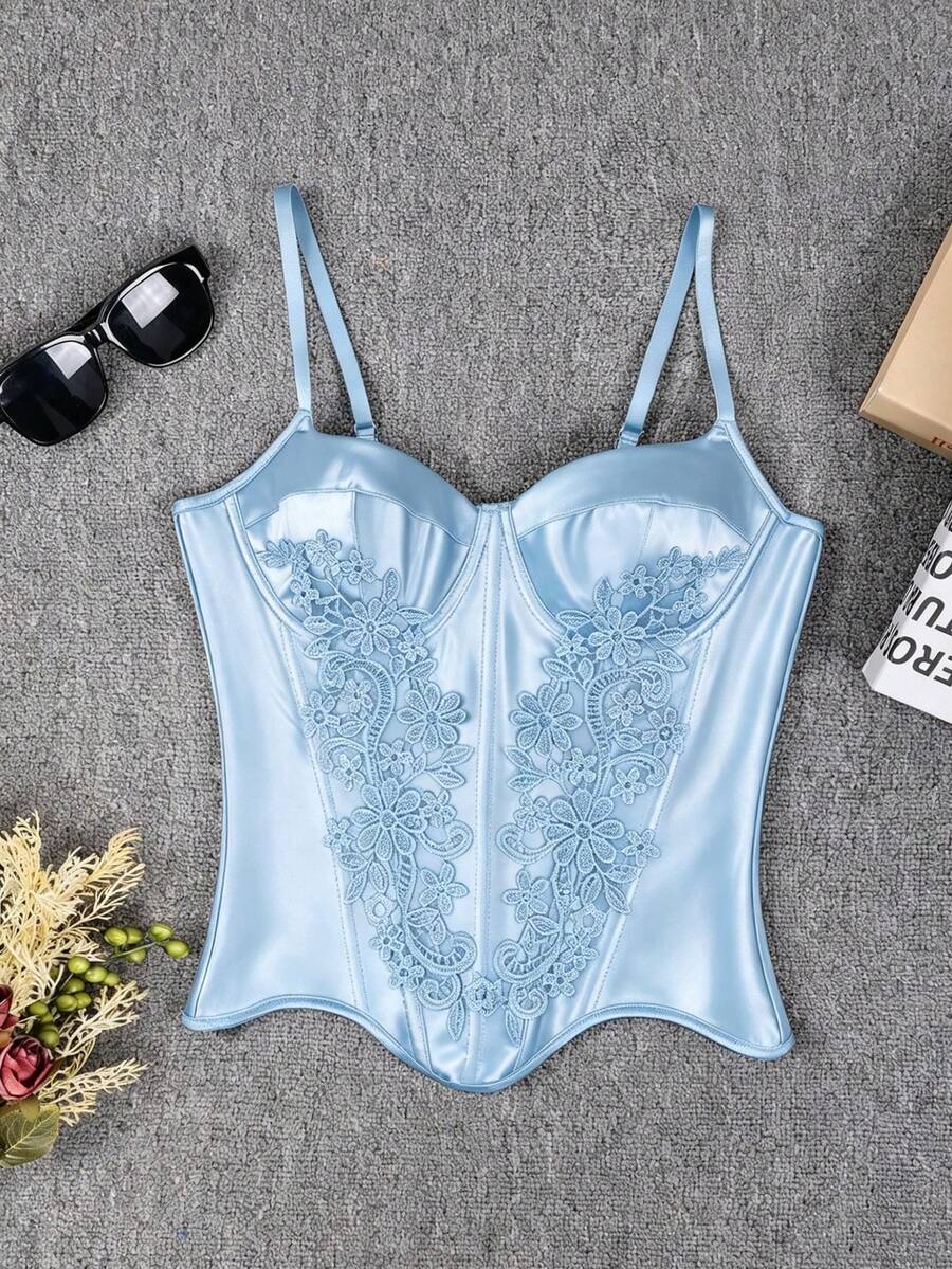 Black satin corset top for women with 3D floral rose details, boned slim-fit bodice, thin spaghetti straps, lace-up open back, and asymmetrical curved hem.