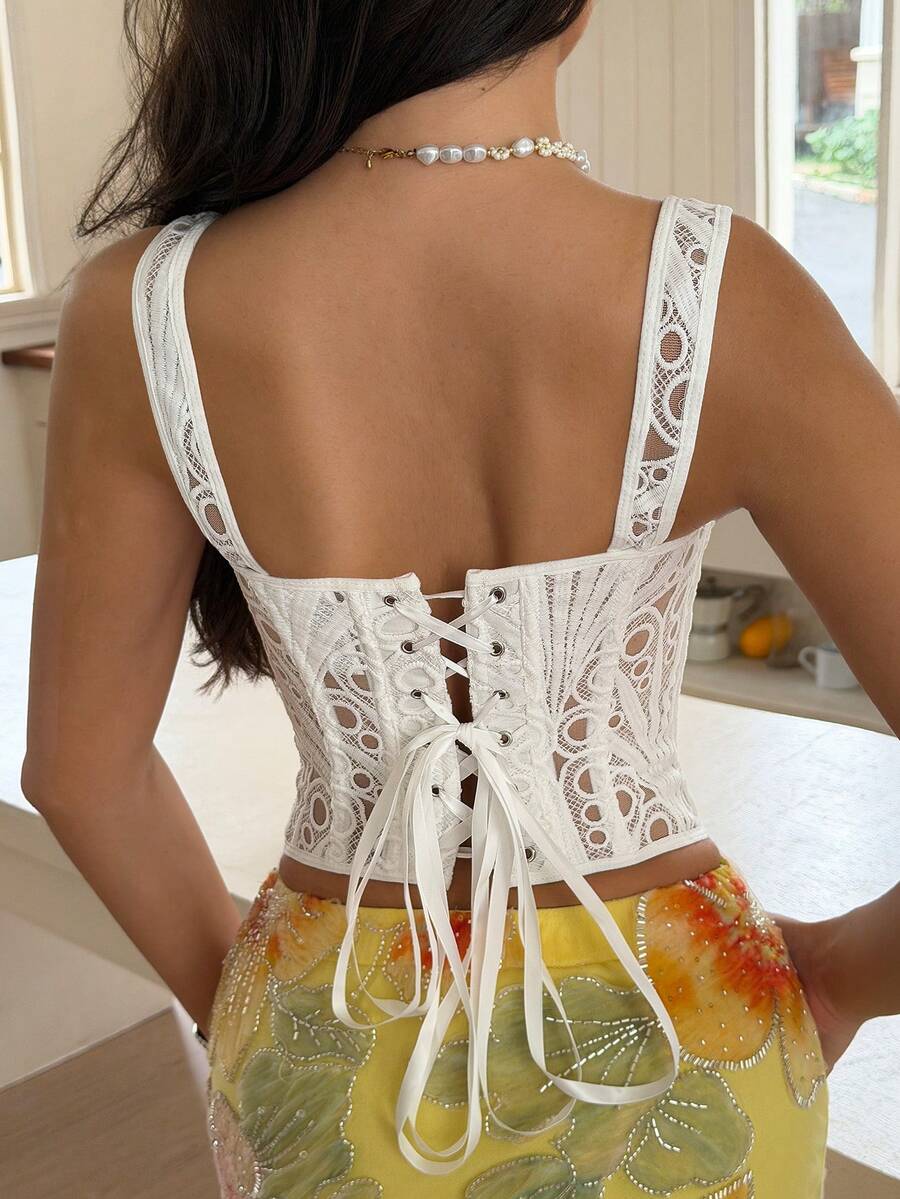 White slim fit boned corset top featuring a square neckline, wide straps, lace-up back, and asymmetrical hem.