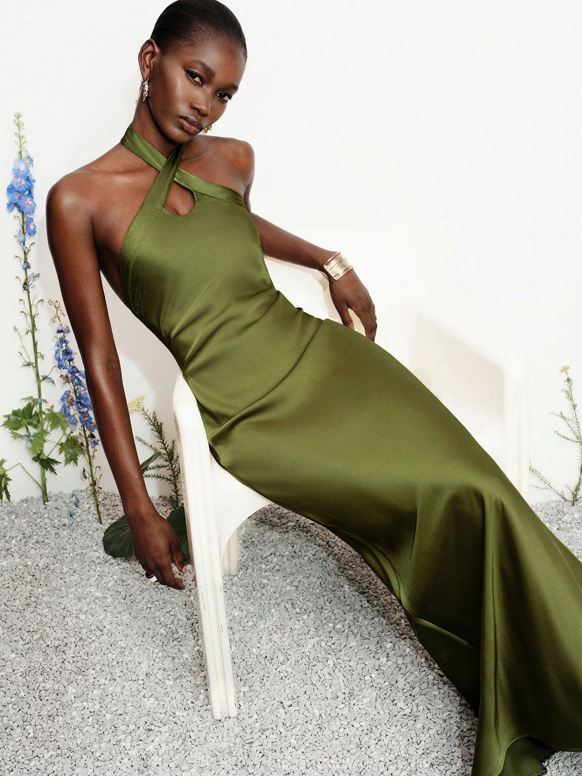 Women's black satin halter neck bodycon midi dress featuring a sleeveless backless design with front slit hem and wrap details.