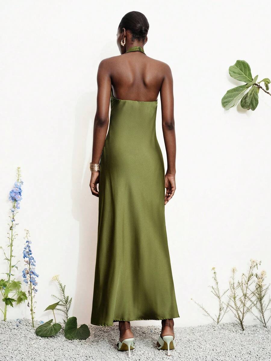 Women's black satin halter neck bodycon midi dress featuring a sleeveless backless design with front slit hem and wrap details.