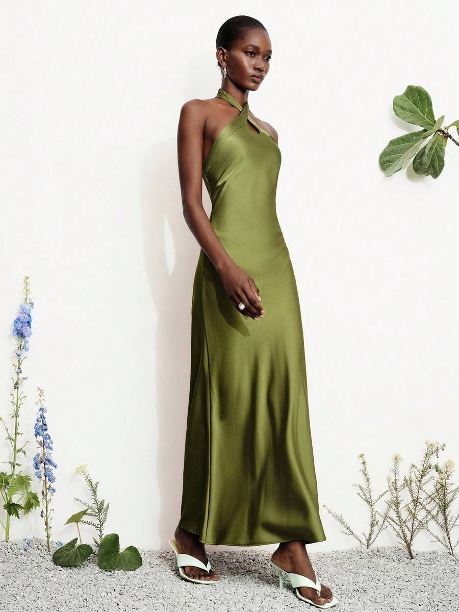 Women's black satin halter neck bodycon midi dress featuring a sleeveless backless design with front slit hem and wrap details.