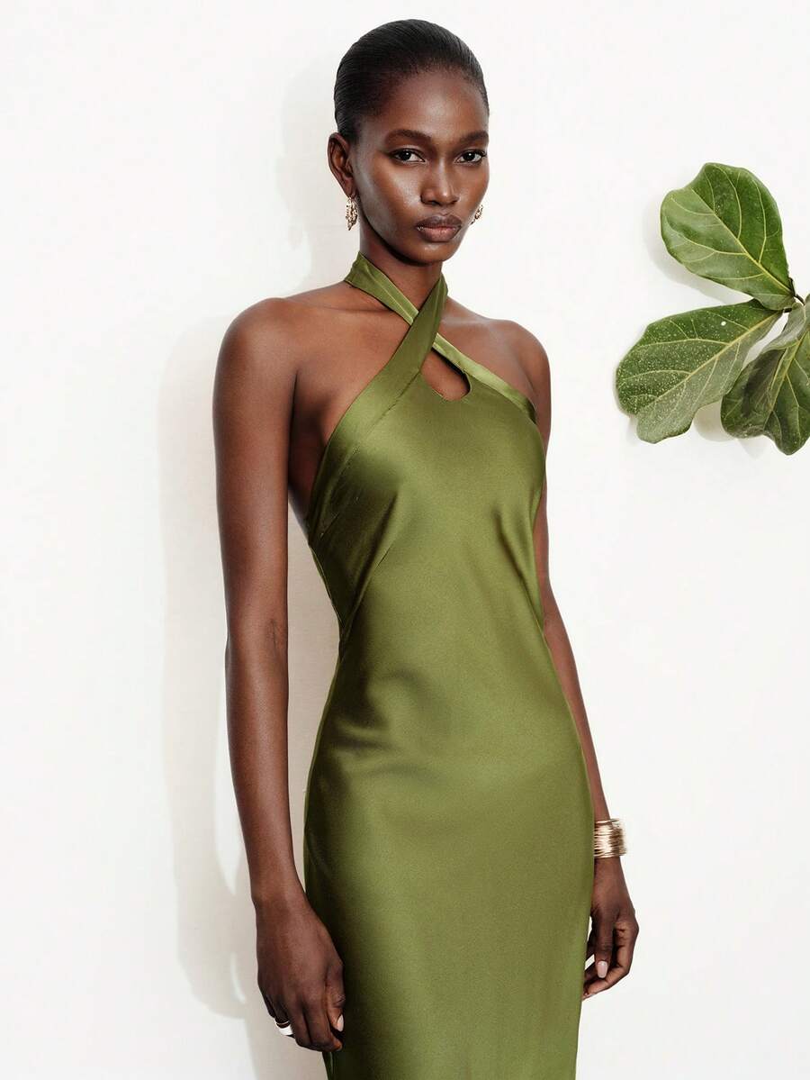 Women's black satin halter neck bodycon midi dress featuring a sleeveless backless design with front slit hem and wrap details.