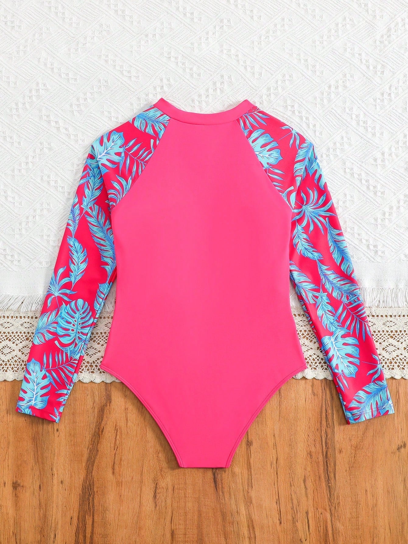 Tween girls one-piece rash guard swimsuit with long sleeves, high neck, front zipper, and ocean shell graphic print in a fitted style for beach, swimming, and vacation wear.