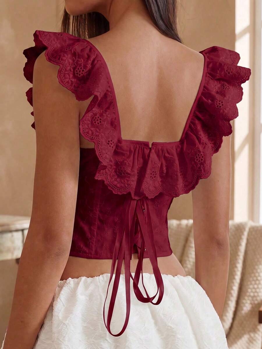 Women’s white corset top with embroidered ruffle trim, off-shoulder neckline, lace-up details, front hook closure, and sleeveless crop fit.