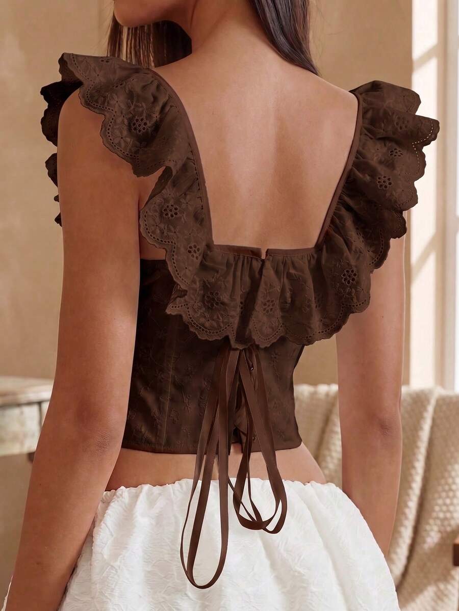 Women’s white corset top with embroidered ruffle trim, off-shoulder neckline, lace-up details, front hook closure, and sleeveless crop fit.