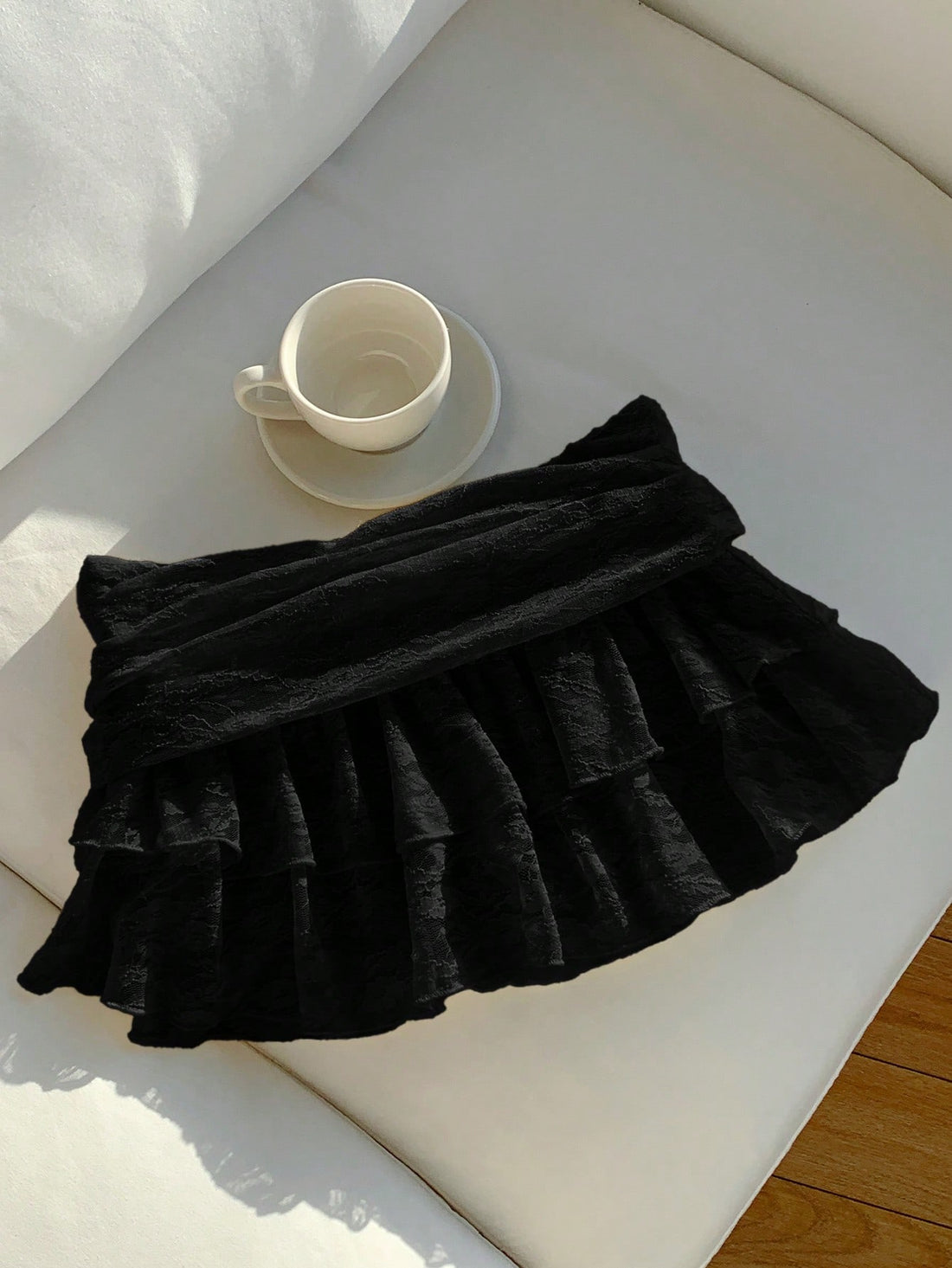 Women's black tiered ruffle mini skirt with low waist fold waistband and layered ruffle hem.