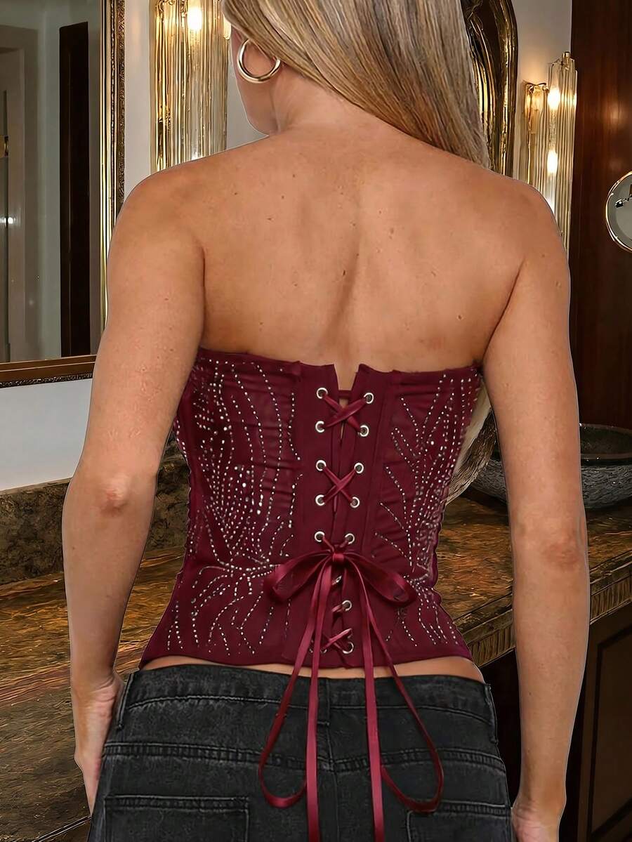 Black strapless corset tube top with sparkling rhinestone decor, boned silhouette, and lace-up tie back.