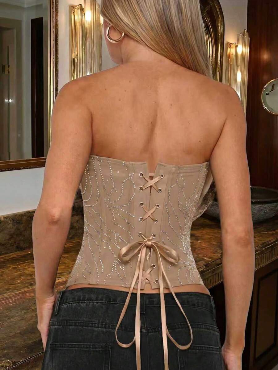Black strapless corset tube top with sparkling rhinestone decor, boned silhouette, and lace-up tie back.