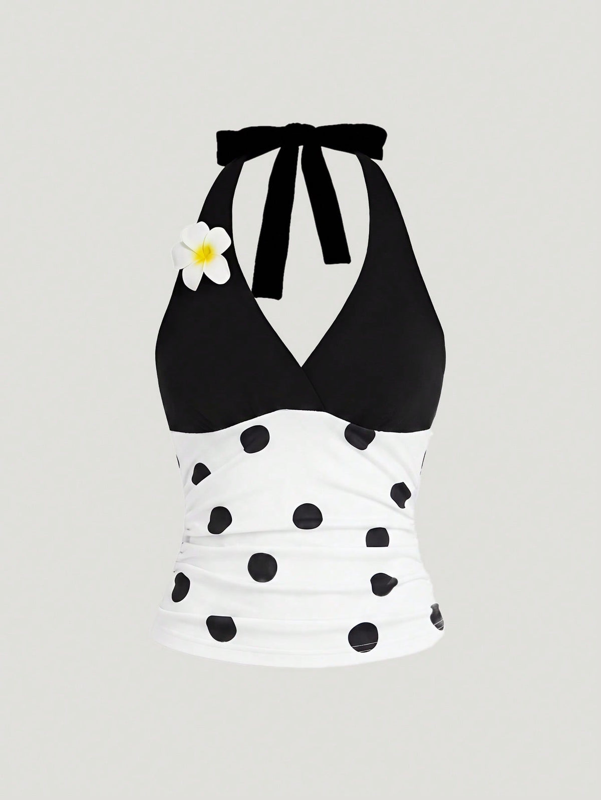 Black and white polka dot halter neck tank top featuring a backless design with ruched knot details and daisy accent.