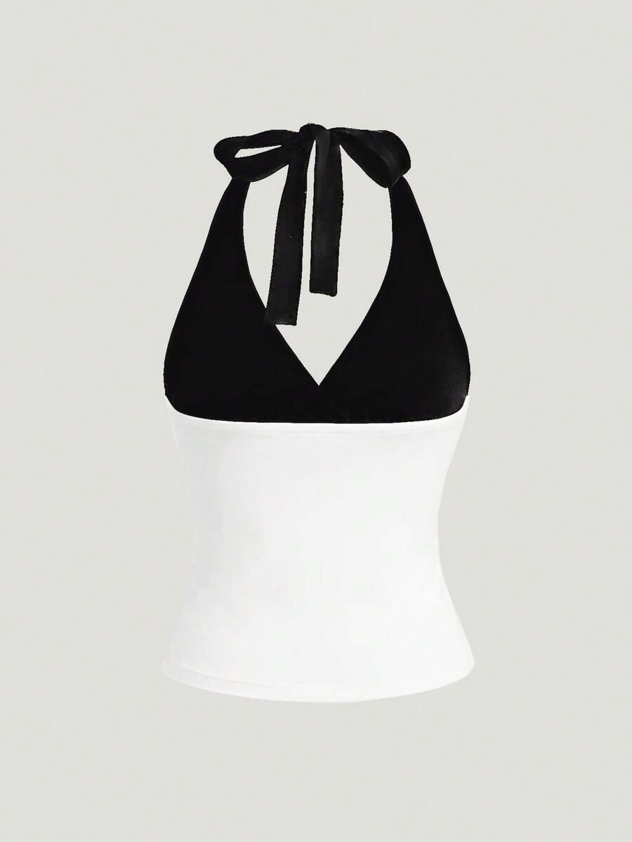 Black and white polka dot halter neck tank top featuring a backless design with ruched knot details and daisy accent.
