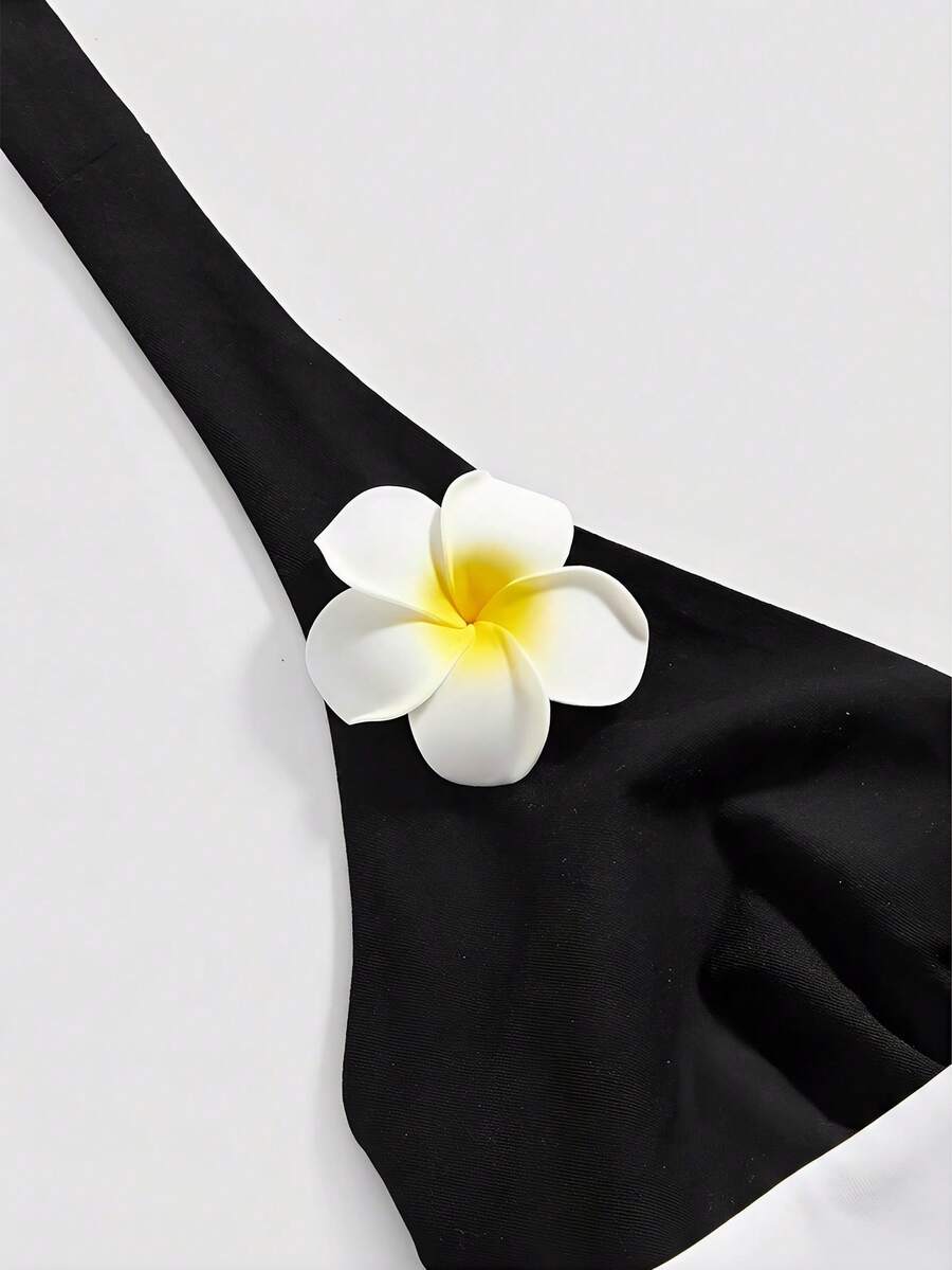 Black and white polka dot halter neck tank top featuring a backless design with ruched knot details and daisy accent.