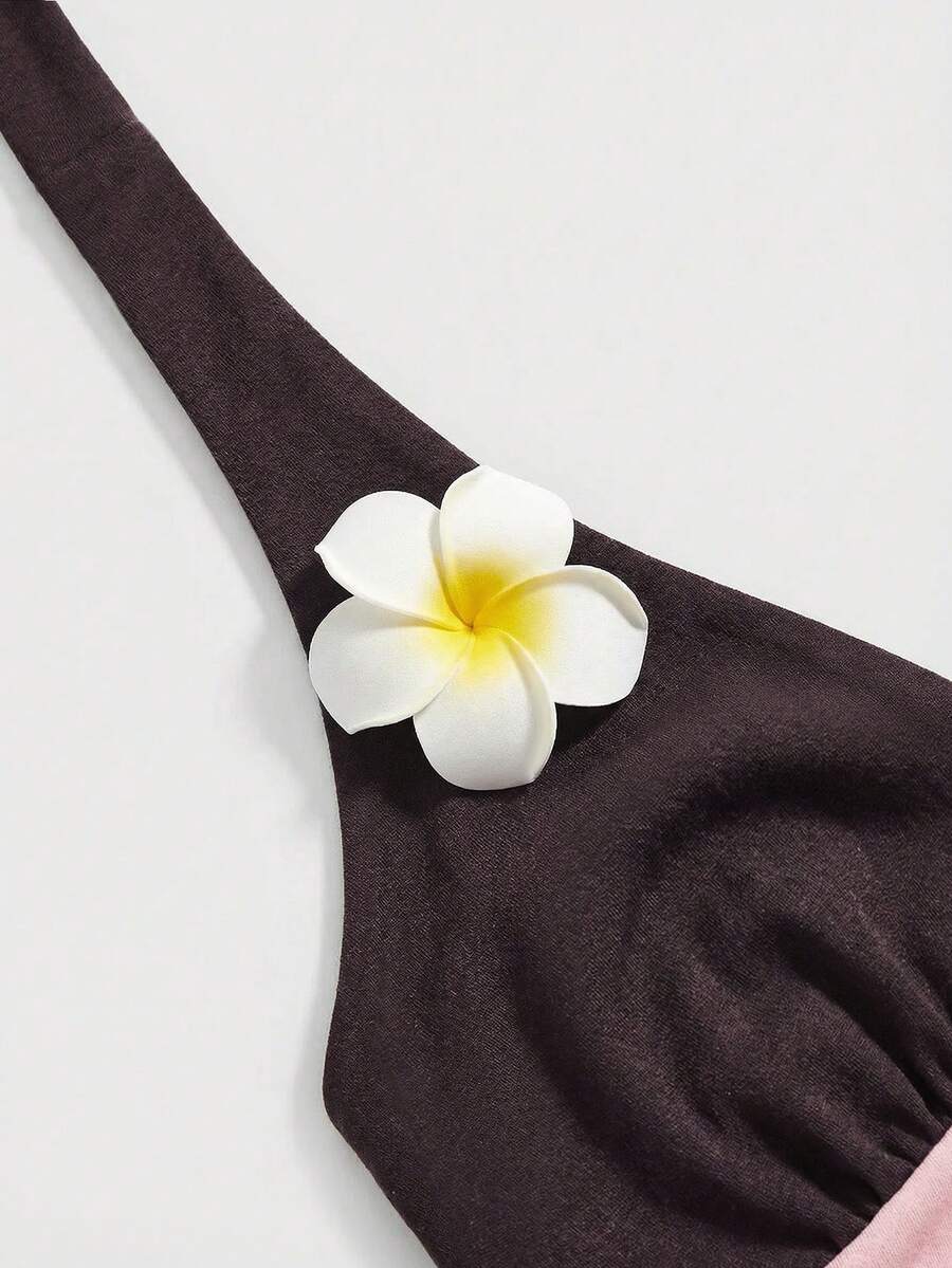 Black and white polka dot halter neck tank top featuring a backless design with ruched knot details and daisy accent.